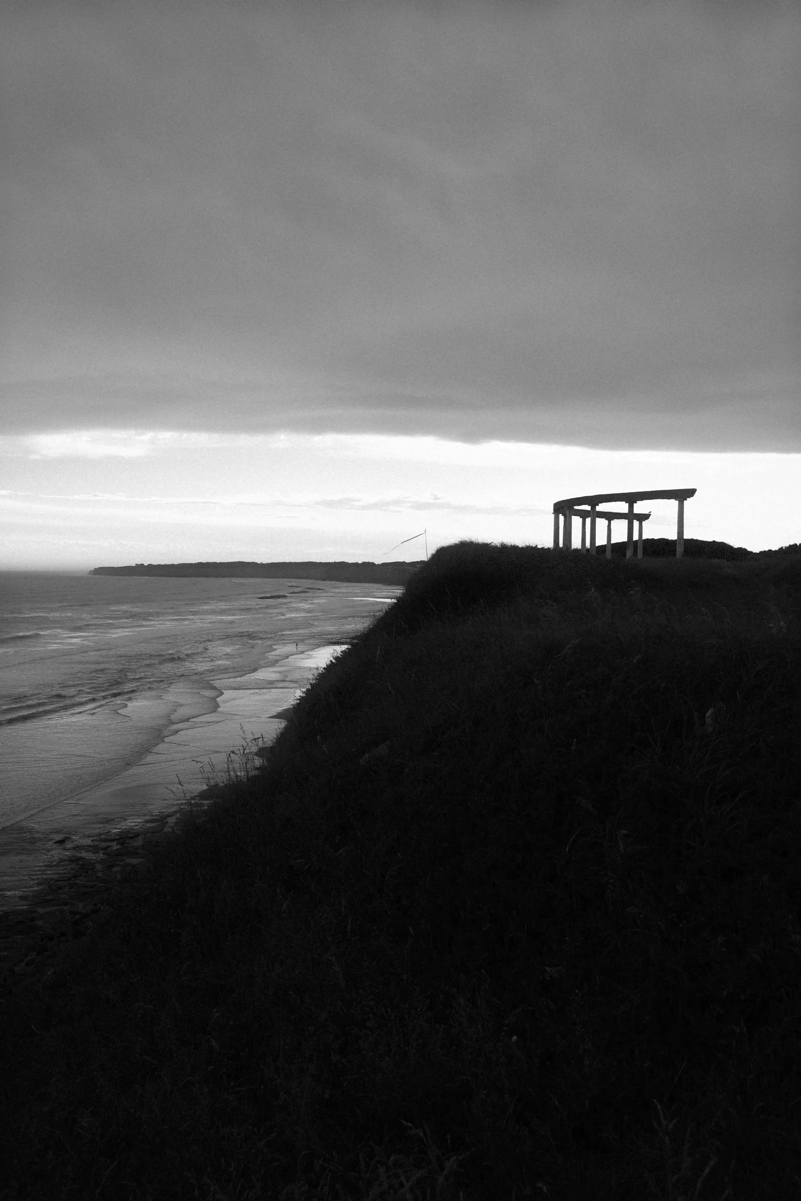 A bench sitting on top of a hill next to the ocean